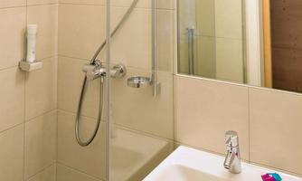 A modern bathroom with a glass shower cabin and a sink. The walls are light, and the fixtures appear clean and inviting.