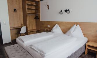 A cozy bedroom with two beds and wooden furniture. The decor is modern and inviting.