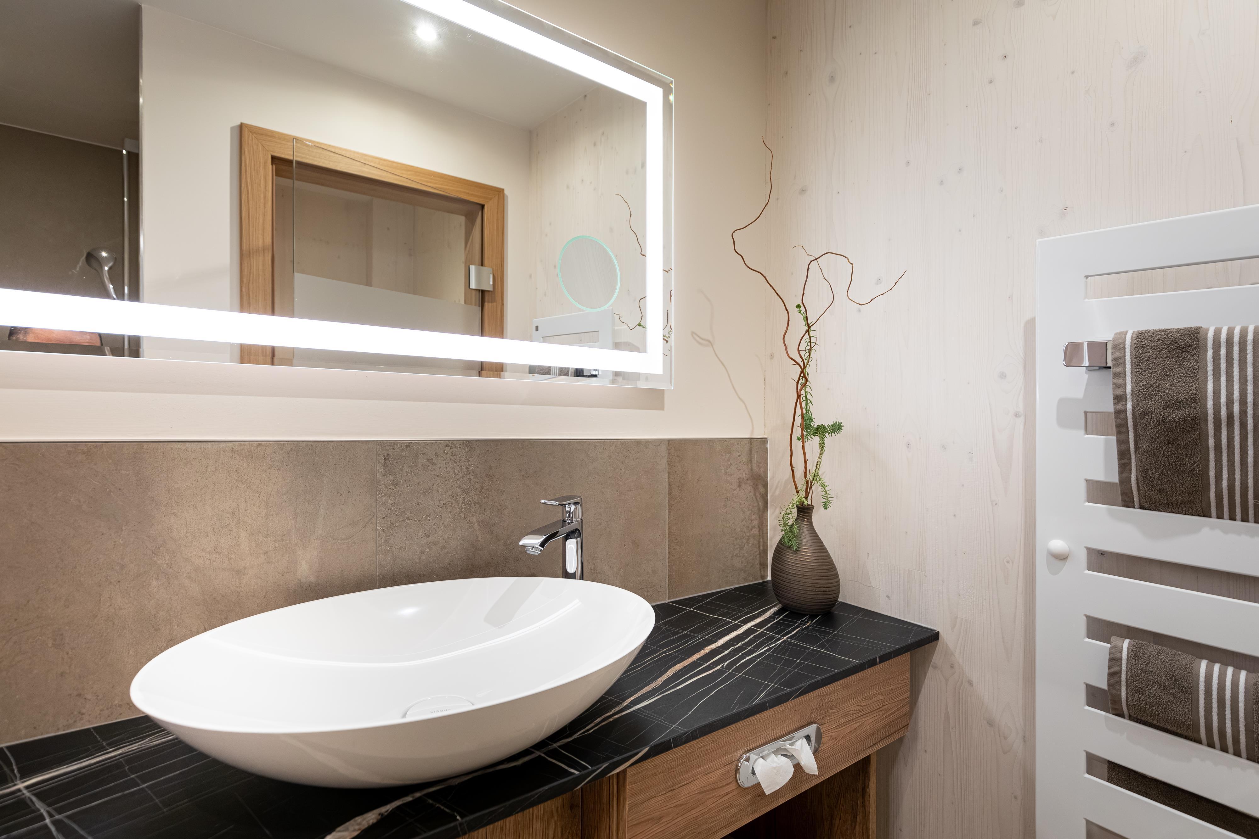 A modern bathroom with an elegant sink and a large mirror. The wood and stone accents create a stylish atmosphere.