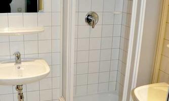 A modern bathroom with a shower and a sink. The walls are tiled and there is a bright, clean decor.