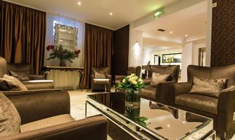 An elegant lounge with comfortable brown armchairs and a glass table. Soft lighting and golden curtains create a cozy atmosphere.