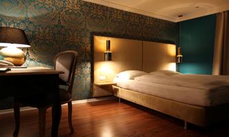 A cozy bedroom with a double bed and an elegant blue wall design. On the table, there is a lamp that provides pleasant lighting.