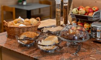A buffet with fresh bread and rolls in baskets. Fruit and snacks are arranged on a table.