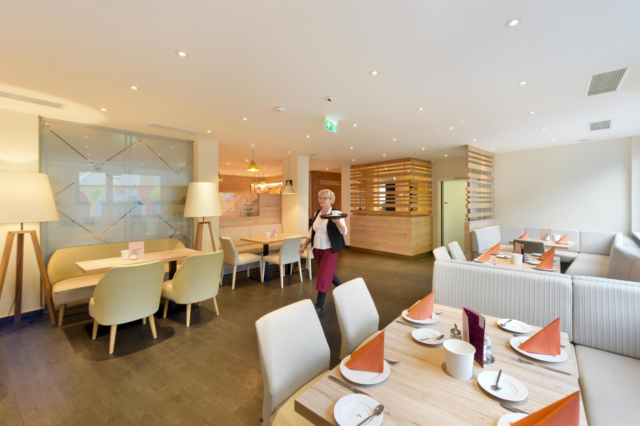 A modern restaurant with stylish furnishings and pleasant lighting. There are several table arrangements that invite you to dine.