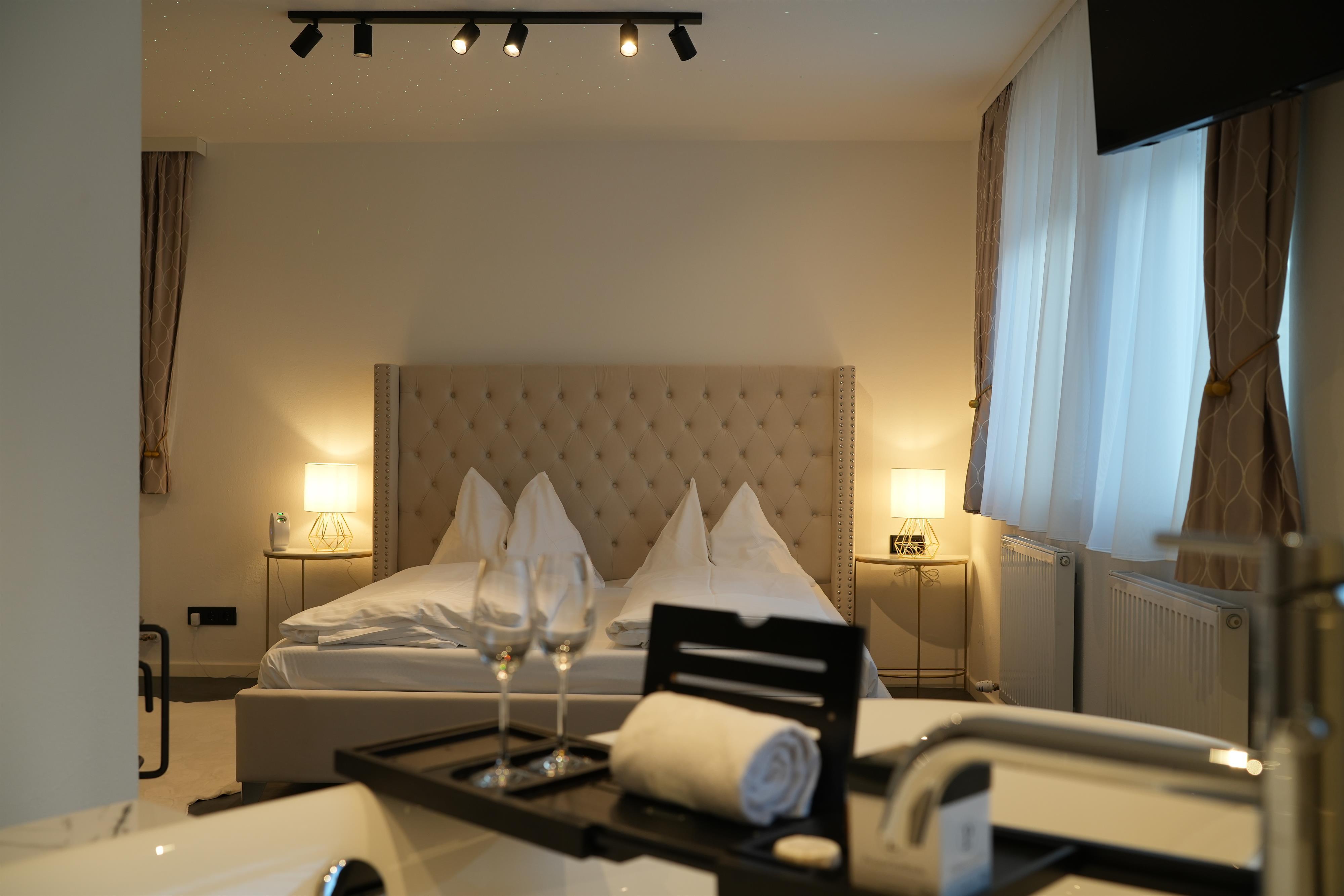 A cozy bedroom with a large double bed and elegant decor. There are two glasses and a towel on a table.