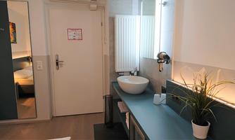 A modern bathroom with a sink and a stylish shelf. The walls are bright and the room is well lit.