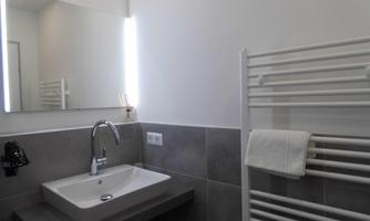 A modern bathroom with a sink and a large mirror. A towel rack hangs on the wall and the room feels bright and inviting.