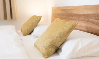 A cozy bedroom with two beds and yellow pillows. The wooden headboard gives the room a warm atmosphere.