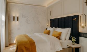 An elegant bedroom with a cozy bed and a stylish wall design. The soft colors and indirect lighting create a relaxing atmosphere.