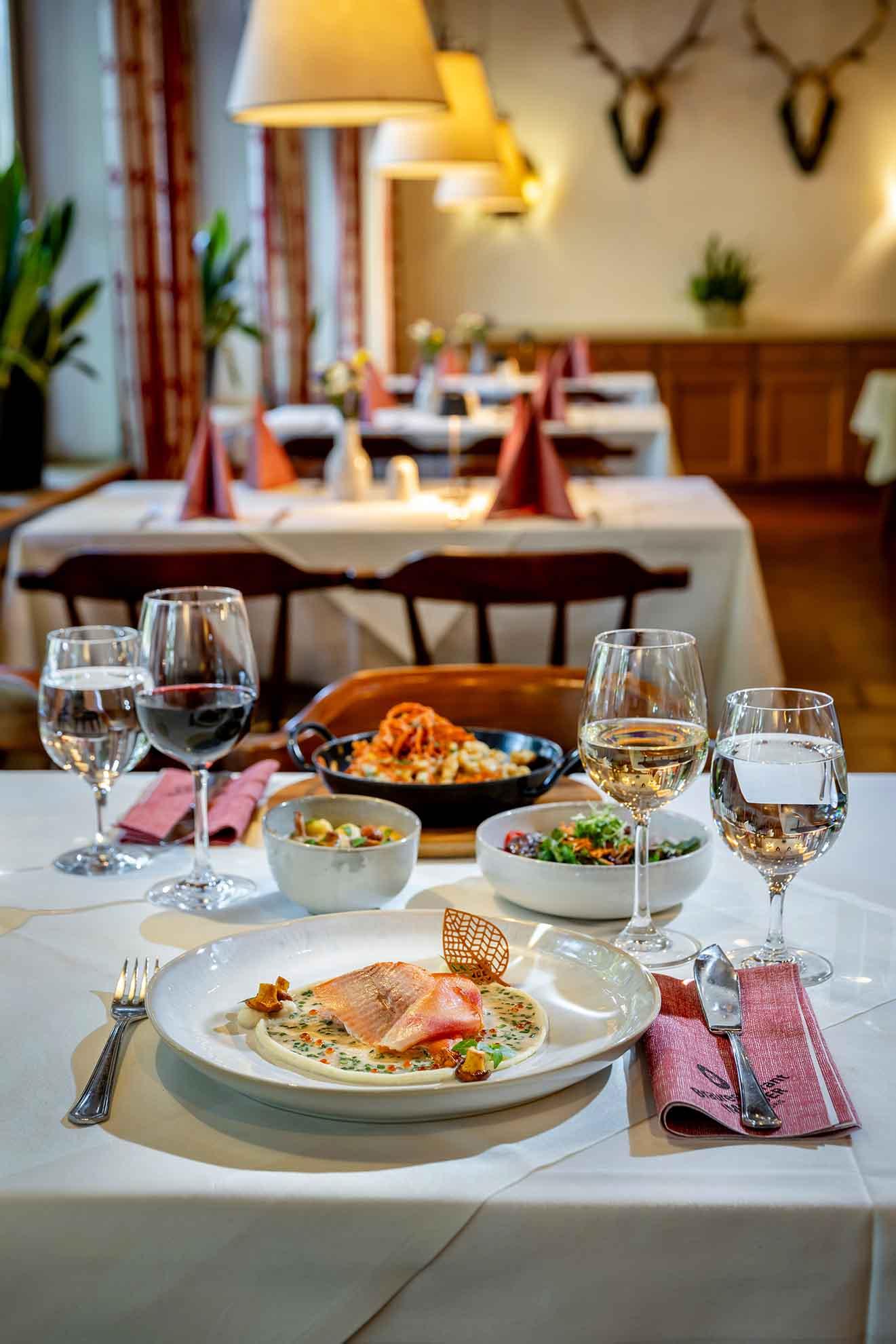 An elegant restaurant with laid tables and stylish lamps. Various dishes and wine glasses are on the table.