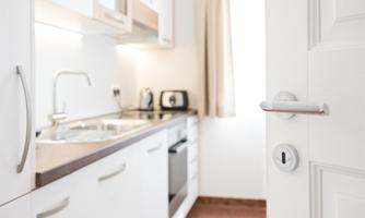 A modern, bright kitchen with white cabinets and a functional layout. The room is clearly visible from the door and invites cooking.
