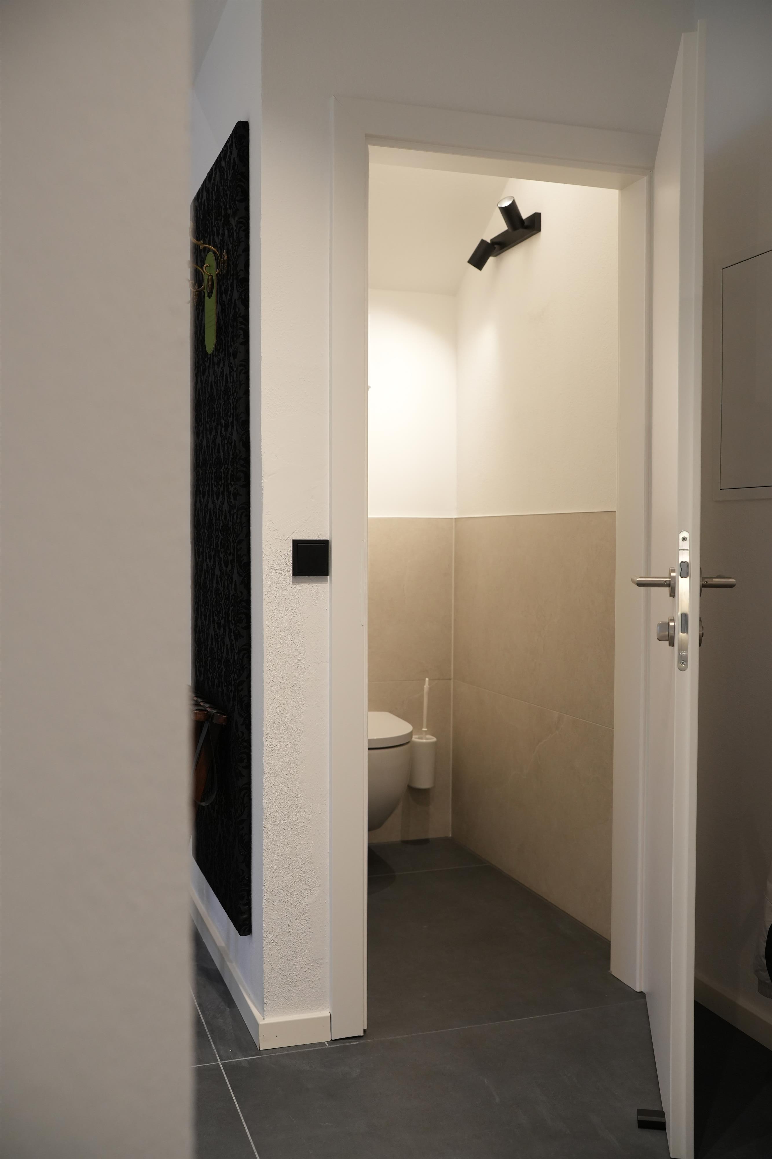 A modern bathroom with an open door. The walls are bright and designed in a minimalist style.
