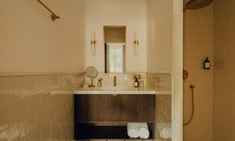 A modern bathroom with an elegant vanity combination and white towels. Light streams through a window, creating a bright atmosphere.