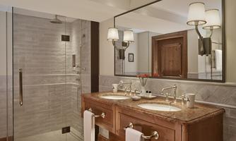 An elegant bathroom with a large glass shower and a double wooden sink. The soft lighting creates a relaxing atmosphere.