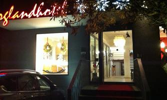 An inviting restaurant with a illuminated facade and a large glass front. The entrance door is open, revealing a warm, welcoming interior.