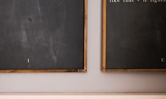 Two black boards with inspiring quotes hang on the wall. Below is a wood-paneled area.