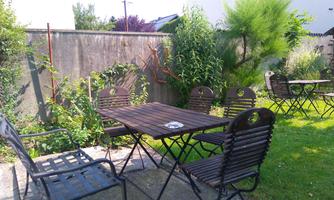 A beautiful garden with a wooden table and chairs. Surrounded by green plants and a peaceful atmosphere.