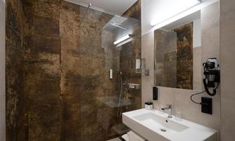 A modern bathroom with a walk-in shower and an elegant sink unit. The walls are designed in warm earth tones.