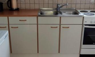 A practical kitchen with a sink, stove, and several cabinets. The kitchen elements are bright and simply designed.