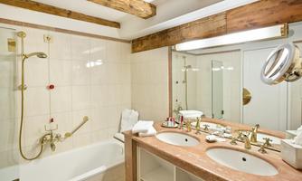 A modern bathroom with a bathtub and two sinks. The wooden beams give the room a cozy atmosphere.