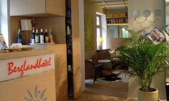 A bright and modern hotel reception with wooden decor. Beverages are on the counter, and a plant creates an inviting atmosphere.
