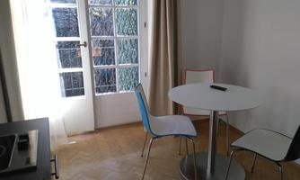 A bright room with a round table and three chairs. Large windows provide a view of the outside.