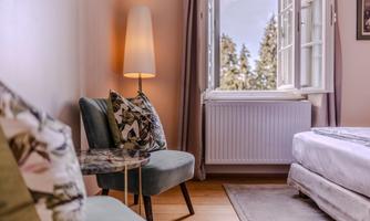 A cozy room with two chairs and a lamp. The window offers a view of nature outside.
