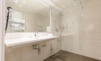 A modern bathroom with bright tiles and a large shower. The space is well-lit and stylishly furnished.