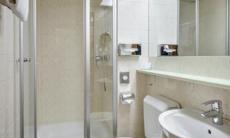 A modern bathroom with a shower and toilet. The walls are light, and the room feels clean and inviting.