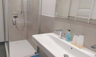 A modern bathroom with a shower and a sink. The decor is bright and clean, with blue and white accents.