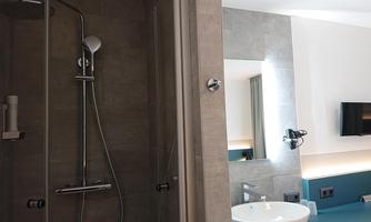 A modern bathroom with a shower and a sink. The room is stylishly equipped with a large mirror and a television.