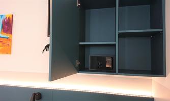 An open, blue cabinet with a digital safe on a shelf. In the background, a colorful picture hangs on the wall.