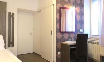 A modern room with a large mirror and a desk. The walls are designed in a colorful, patterned style.