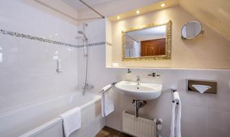 A modern bathroom with a bathtub and a sink. The walls are light and there is a large mirror.