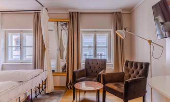A modern room with two comfortable armchairs and a small table. Bright curtains and a television on the wall create a cozy atmosphere.