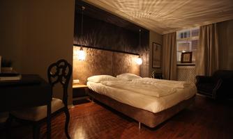 A cozy bedroom with a large bed and warm light. Stylish furniture complements the inviting atmosphere.