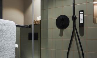 A modern bathroom with a shower and an elegant toilet. The walls are tiled in soft shades of green.