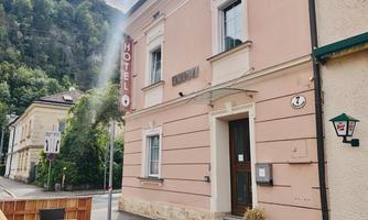 A charming hotel building with a striking sign. Surrounded by green hills and a quiet road.