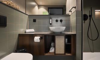 A modern bathroom with a beautiful wooden shelf and a large sink. The walls are painted in soft green and gray tones.