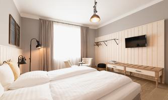 A modern bedroom with a large double bed. The room is bright and friendly, with a window and minimalist design.