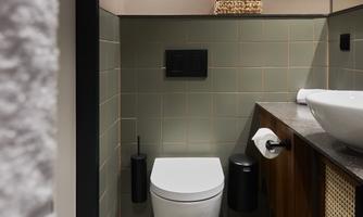 A modern bathroom with a stylish toilet and an elegant sink. The walls are in soft colors and the floor is made of fine stone.