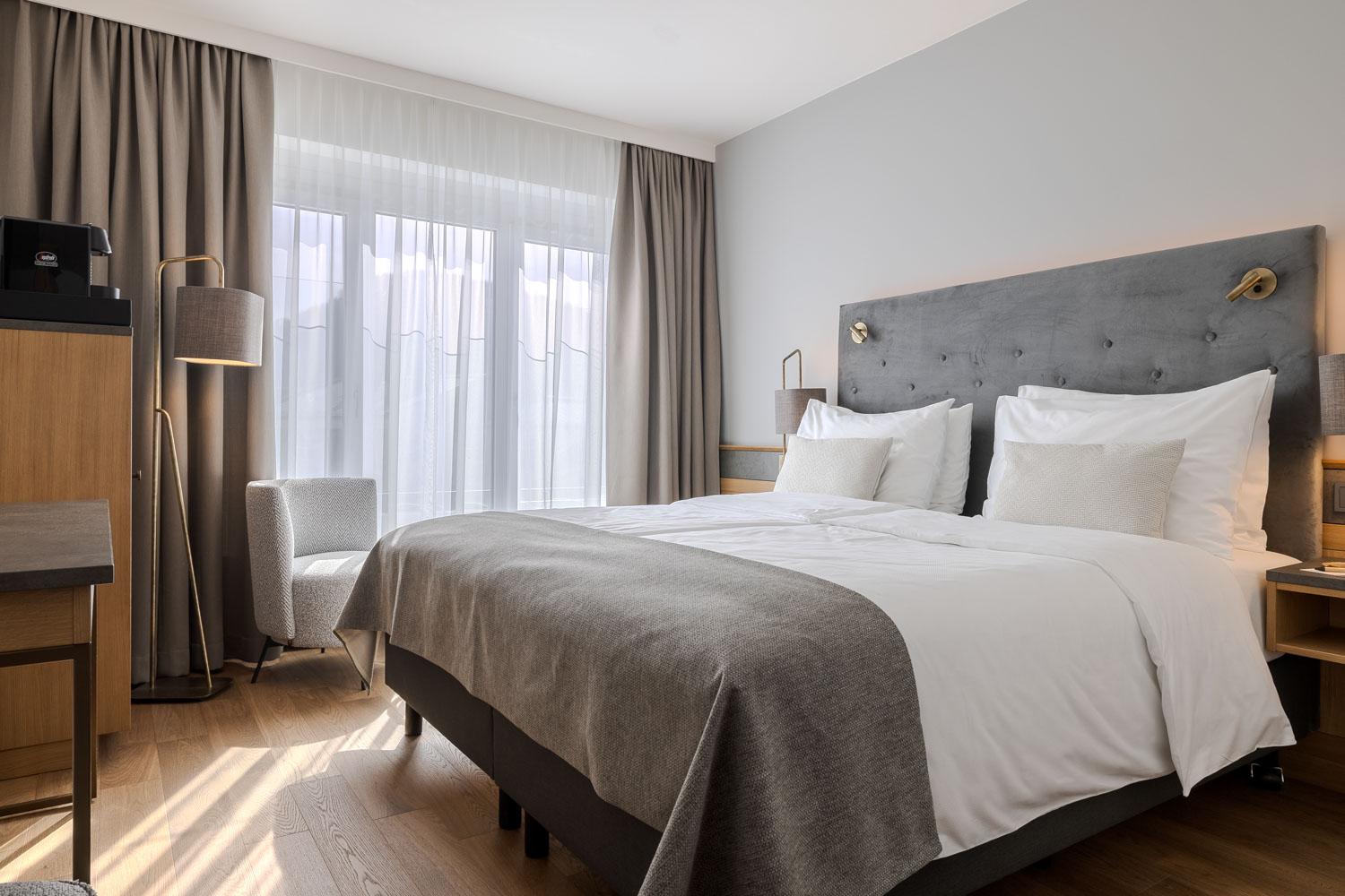 A modern bedroom with a large double bed and elegant furnishings.  
Bright curtains create a cozy atmosphere.
