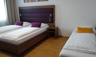 A cozy room with a double bed and a single bed. Large windows provide plenty of natural light.