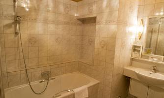 A stylish bathroom with a bathtub and a separate shower. The room is bright and modernly designed, with a sink and large mirror.