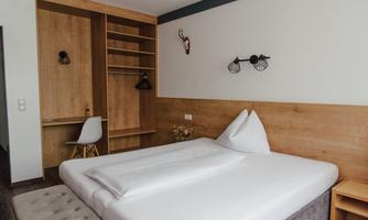 A simple and modern bedroom with a bed and wooden decor. There is a desk and storage space in the room.