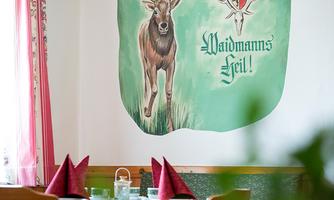 A cozy dining area with a mural of a deer on the wall. Decorative napkins and glasses are on the table.