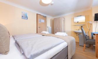 A cozy bedroom with two beds, bright walls, and modern furniture. A television is on a table, and a chair is placed next to it.