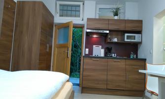 A cozy room with wooden furniture and a small kitchen. There is a large wardrobe and a table with chairs.