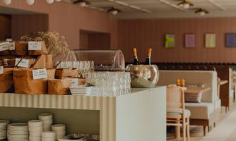 A modern café with minimalist decor and bright colors. The reception counter is adorned with dishes and drinks.