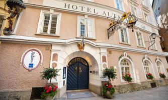 A charming hotel with an elegant facade in soft colors. Colorful flowers adorn the entrance, creating an inviting atmosphere.